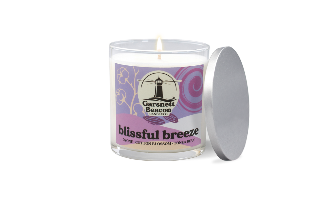 Candle labeled 'blissful breeze' on a table with a scenic background
