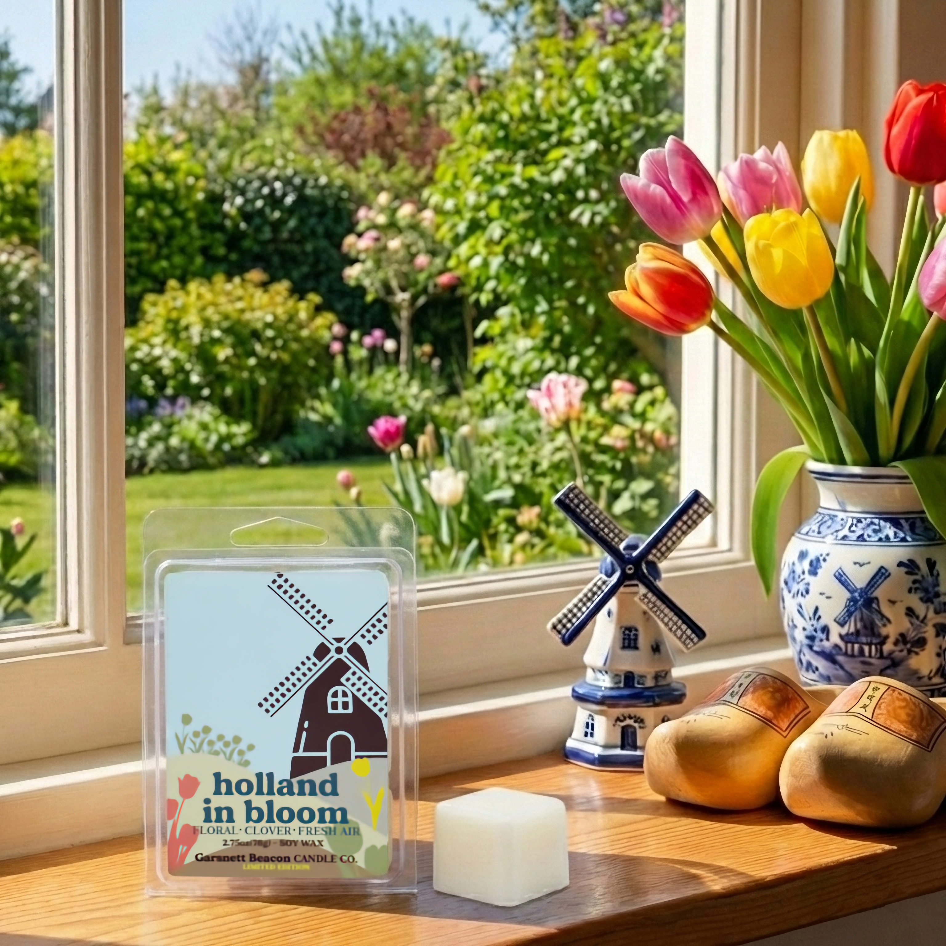 Wax melts with 'Holland in Bloom' packaging, windmill decoration, and tulips in a vase on a windowsill.