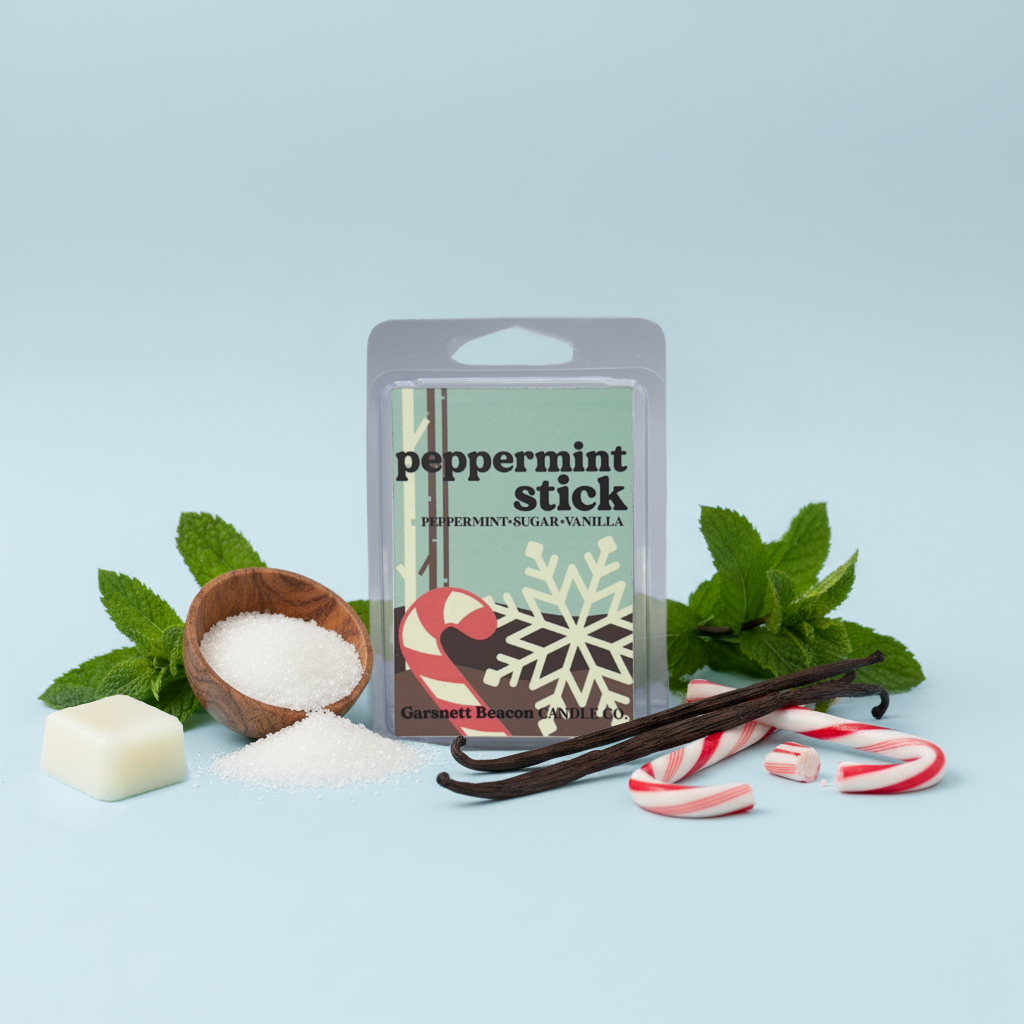 Peppermint stick wax melt packaging with mint leaves, sugar, and candy canes on a light blue background
