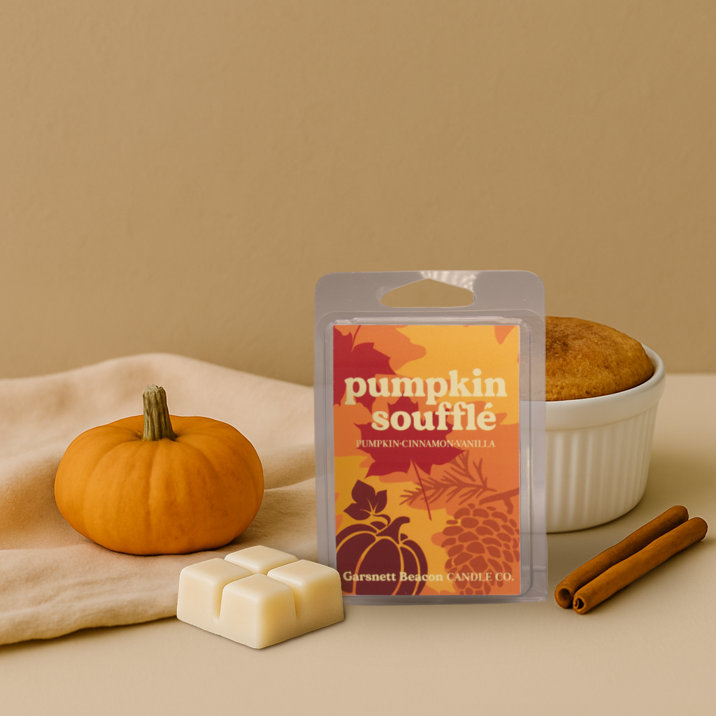Pumpkin souffle wax melt package with a pumpkin, cinnamon stick, and bowl of cake on a beige background