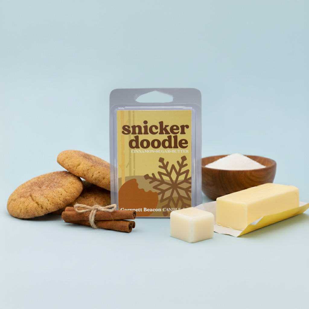 Snickerdoodle-themed wax melt with cookies, cinnamon, and a wax bar on a light blue background