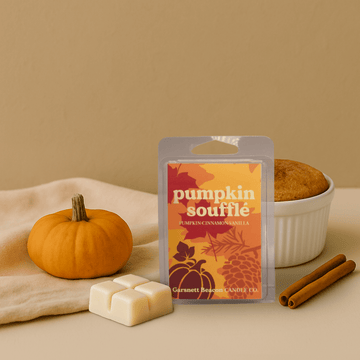 Pumpkin souffle wax melt package with a pumpkin, cinnamon stick, and bowl of cake on a beige background