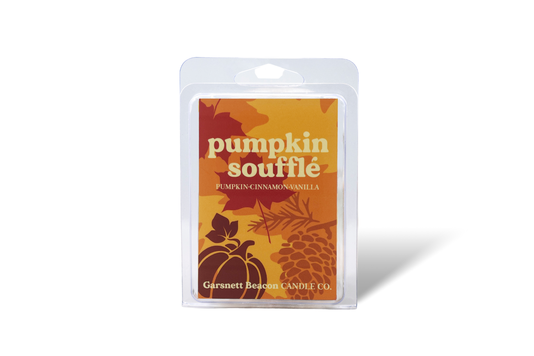 Pumpkin souffle wax melt package with a pumpkin, cinnamon stick, and bowl of cake on a beige background
