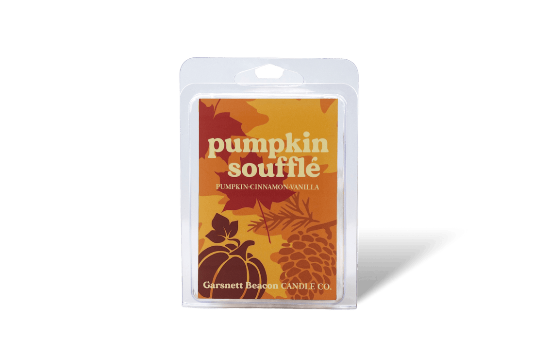 Pumpkin souffle wax melt package with a pumpkin, cinnamon stick, and bowl of cake on a beige background
