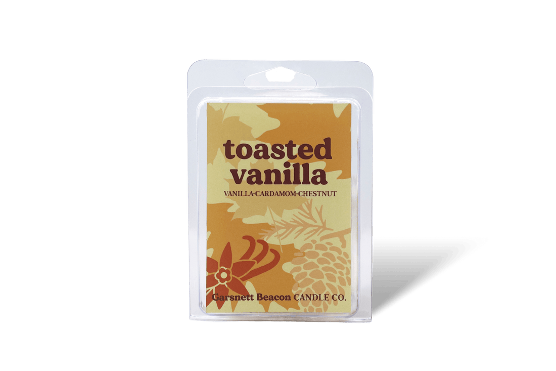 Scented wax melt 'Toasted Vanilla' with chestnuts, vanilla beans, and a bowl of spices on a beige background.